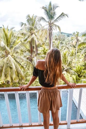 a little girl standing on a balcony looking out at the ocean at Good Vibes Villas in Unawatuna