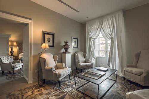 a living room with chairs and a table and a window at Seven Rooms Villadorata in Noto