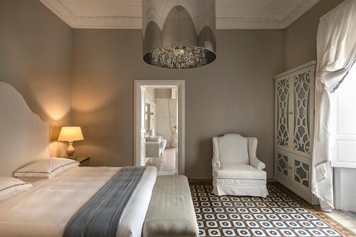 a bedroom with a bed and a chair and a chandelier at Seven Rooms Villadorata in Noto