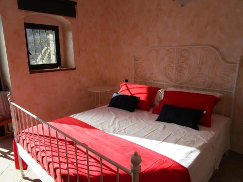 a bedroom with a bed with red and white pillows at Alla Contrada degli Asinelli in Colledanchise