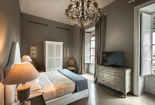 a bedroom with a bed and a television and a chandelier at Seven Rooms Villadorata in Noto