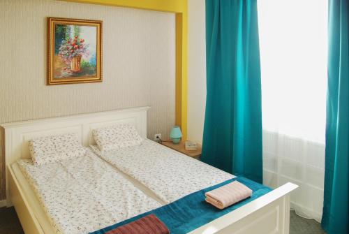 a bedroom with a white bed with blue curtains at City Home Timisoara in Timişoara