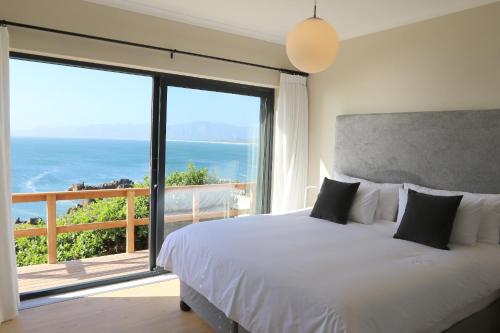 a bedroom with a bed and a large window at Cliff Lodge in Gansbaai