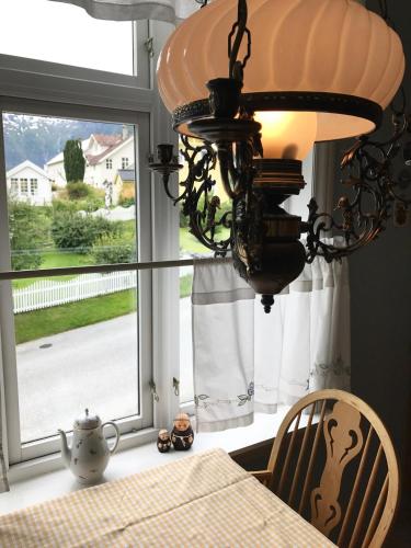 a dining room table with a chandelier and a window at Villa Holmen in Balestrand