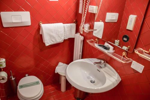 Baño rojo con lavabo y aseo en Hotel Le Boulevard, en Lido de Venecia