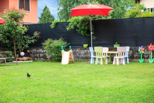 a table and chairs with a red umbrella in a yard at Casa Allegra in Orta San Giulio