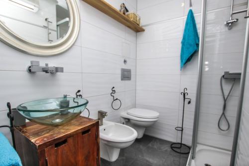 a bathroom with a sink and a toilet and a mirror at Apartman Kika in Poreč