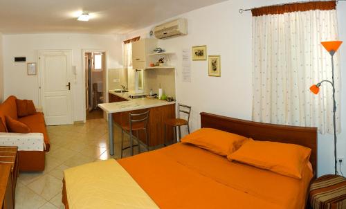 a bedroom with an orange bed and a kitchen at Apartment Santa Croce Free Parking in Rovinj