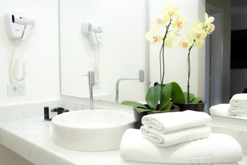 W białej łazience znajduje się umywalka i lustro. w obiekcie Pousada Larimor w mieście Boiçucanga