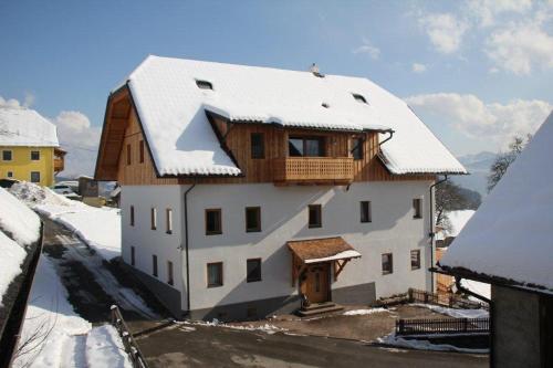 a white house with snow on the roof at Landhaus Löscher in Seeboden