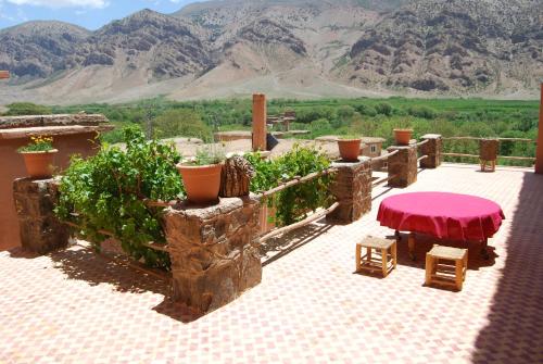 a patio with a red table and a view of mountains at Kasbah Ait Bouguemez in Agouti