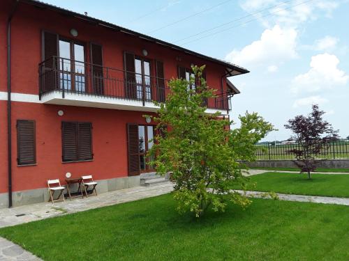 ein rotes Haus mit zwei Stühlen und einem Baum davor in der Unterkunft Tra MENTA e MELIGA in Carignano