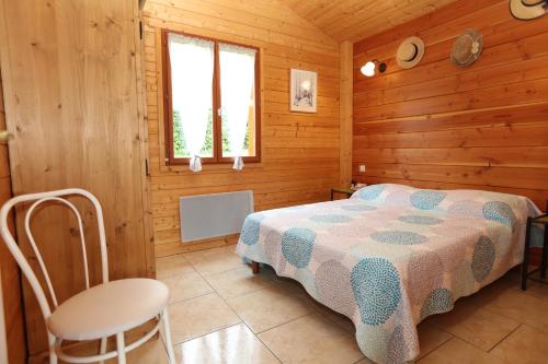 een slaapkamer met een bed en een stoel in een hut bij Chalet de Grettery in Saulxures-sur-Moselotte