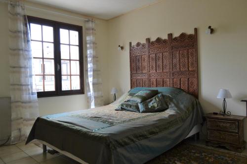 モンタニャックにあるGîte (Annexe de La perle de Ceylan)のベッドルーム1室(木製ヘッドボードと窓付)