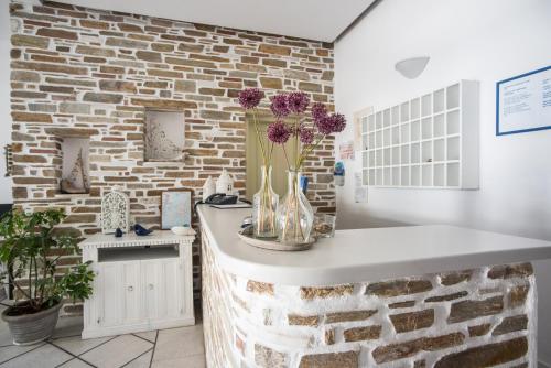 a kitchen with a brick wall and a counter with flowers in a vase at Hotel Mantalena in Antiparos