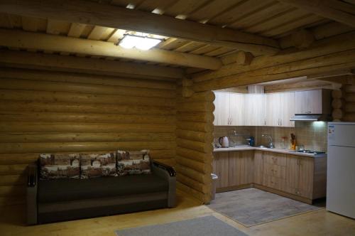uma cozinha com um sofá numa cabana de madeira em Guest House Smerichka em Shaian
