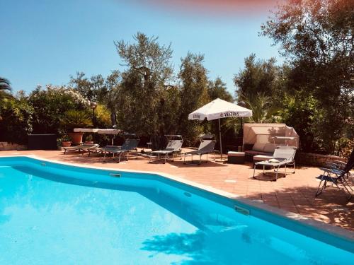 uma piscina com cadeiras e um guarda-sol em Villa Monica appartamenti em Vieste