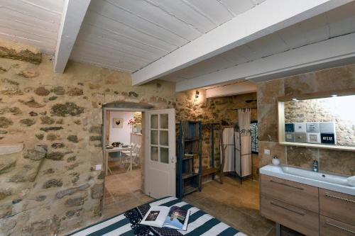 een badkamer met een stenen muur en een wastafel bij Le petit trésor du Luberon in Ménerbes