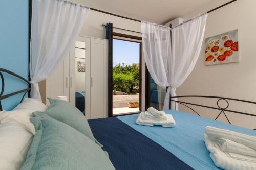 a bedroom with a blue bed and a window at Lumia e Zagara in Taormina