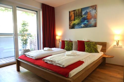 ツェル・アム・ゼーにあるAlpin & See Resortのベッドルーム1室(大型ベッド1台、赤と緑の枕付)