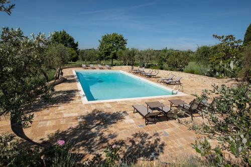 a swimming pool with chaises and chairs in a yard at Borgo Argiano in Castelnuovo Berardenga