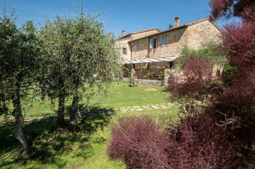 an old stone house with trees in front of it at Borgo Argiano in Castelnuovo Berardenga