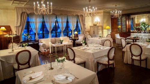 un ristorante con tavoli e sedie bianchi e lampadari a braccio di Kendov Dvorec a Spodnja Idrija