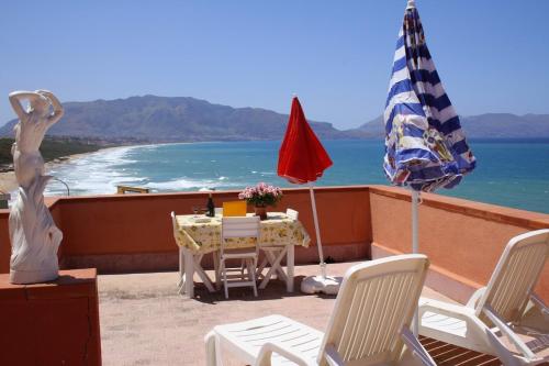 a patio with a table and an umbrella and the ocean at GB Case Vacanze Sicilia in Balestrate