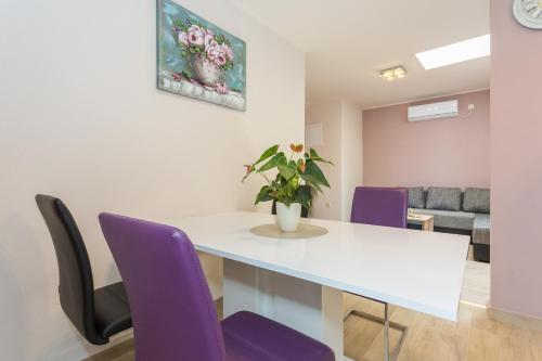 a dining room with a white table and purple chairs at New apartment with terrace and sea view in Lopud Island