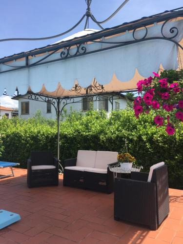a patio with two chairs and an umbrella and flowers at B&B Il Portico in Sarzana