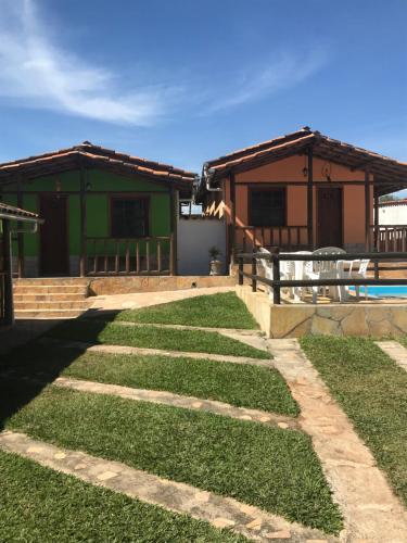 a grassy yard with two buildings and a house at Pousada Recanto das pedras in São Gonçalo do Rio das Pedras