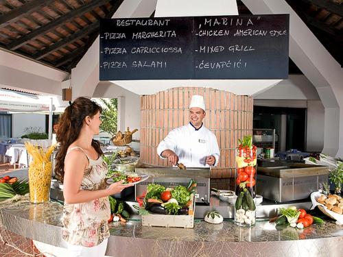a woman standing in front of a kitchen with a chef at Lanterna Resort in Tar