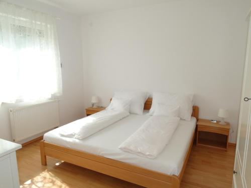 een slaapkamer met een bed met witte lakens en kussens bij House Magnolia in Velence