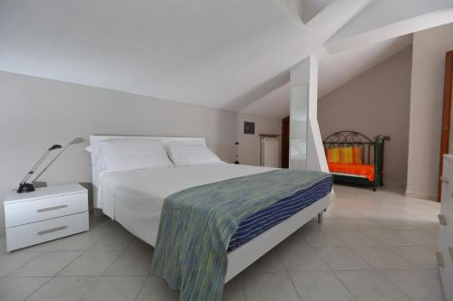1 dormitorio con 1 cama blanca grande y 1 silla naranja en Maren, en Nizza Monferrato