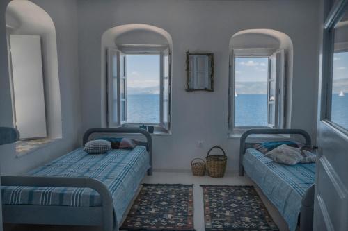 two beds in a room with two windows at Lotus Sweet Home Hydra in Hydra