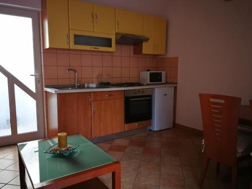 eine Küche mit Holzschränken, einem Tisch und einer Mikrowelle in der Unterkunft Marko Apartment in Pula