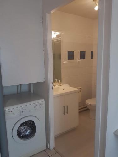 une salle de bain avec machine à laver et toilettes dans l'établissement Le Cosy de Tasdon, à La Rochelle