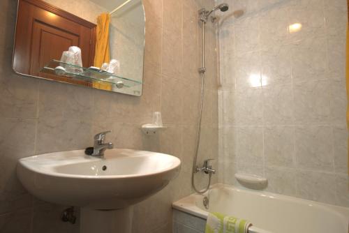 a bathroom with a sink and a mirror and a tub at Hostal San Roque in Portonovo