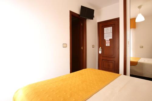 a bedroom with a yellow bed and a door at Hostal San Roque in Portonovo