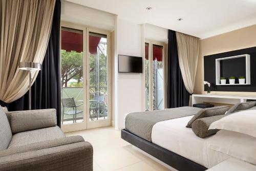 a bedroom with a bed and a couch and a tv at Riva Del Sole Resort & SPA in Castiglione della Pescaia