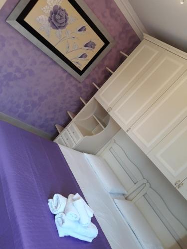 um quarto com uma cama roxa com uma boneca em B&B LADY JOLANDA em Porto Cesareo