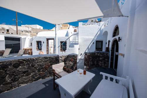a balcony with a table and chairs and buildings at Caves 1880 in Oia