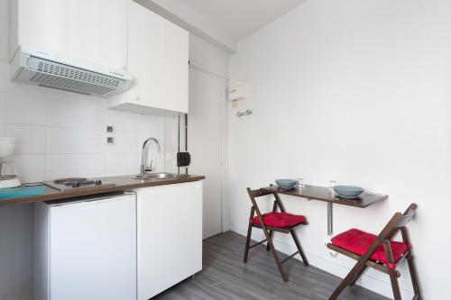 eine Küche mit 2 Stühlen und einem Tisch in der Unterkunft Studio Meublé in Gentilly