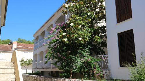 a building with a flowering tree in front of it at Apartment Ena - Lavica in Podstrana