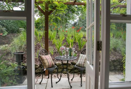 a patio with a table and chairs in a garden at Raheen House Hotel in Clonmel