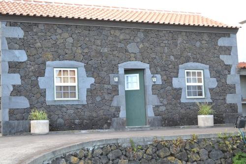 a stone building with a green door and two windows at Adega Mendes in Porto Martins