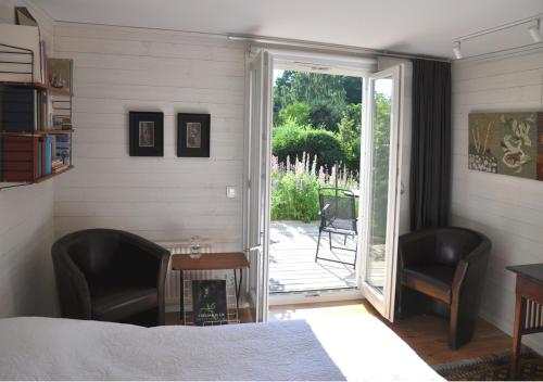 a bedroom with a bed and two chairs and a sliding glass door at Room In Ekestad in Ekestad