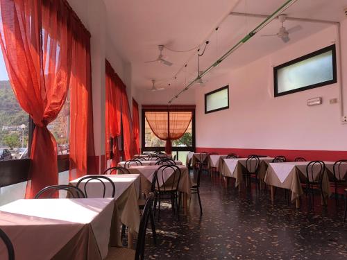 ein Zimmer mit Tischen und Stühlen und roten Vorhängen in der Unterkunft Hotel Monique in Noli