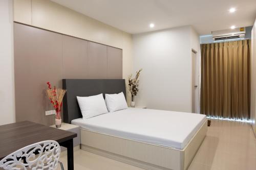 a bedroom with a white bed and a table and a chair at DB Plus 5 in Bangkok