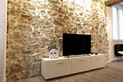 - un salon avec une télévision sur un mur en pierre dans l'établissement GregBnb - T2 Ancien et moderne - PARKING INCLUS - 15min Gare, à Toulon